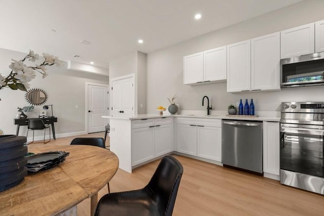 1 Cross St Unit 205, Wilmington, MA 01887 - kitchen featuring stainless steel appliances, a sink, a peninsula, light countertops, and light wood-style flooring