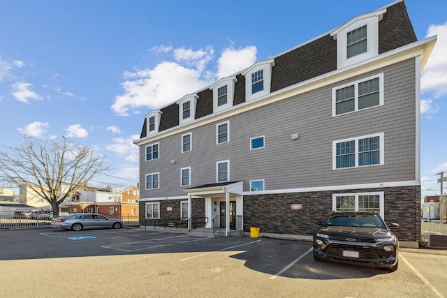 view of property featuring central air condition unit and uncovered parking