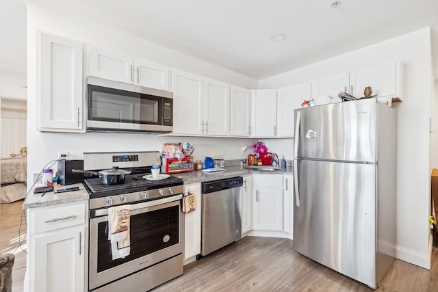 kitchen featuring light wood finished floors, white cabinets, and stainless steel appliances