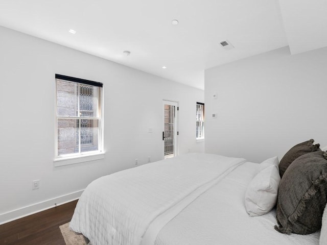 bedroom featuring multiple windows and dark hardwood / wood-style flooring