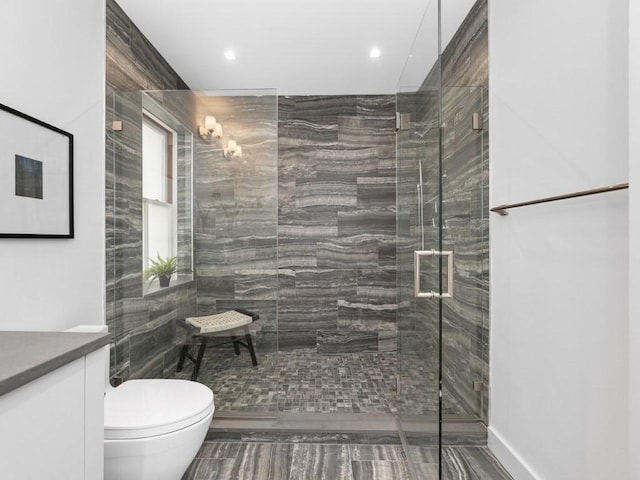 bathroom with vanity, toilet, and a shower with door