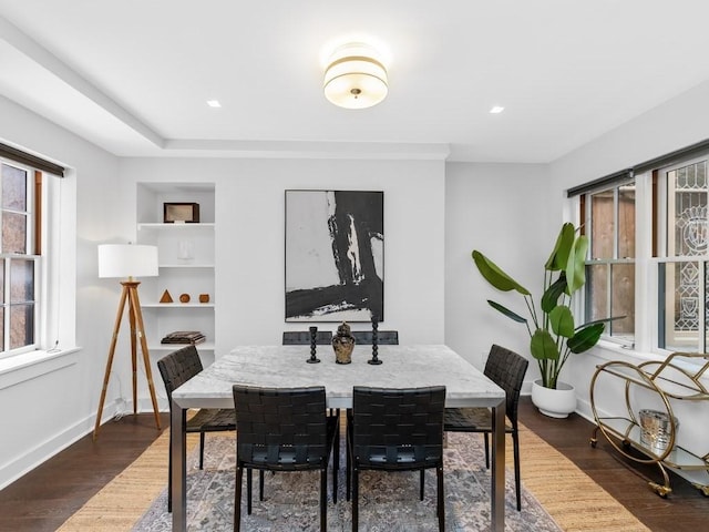 dining space with built in shelves and dark hardwood / wood-style flooring