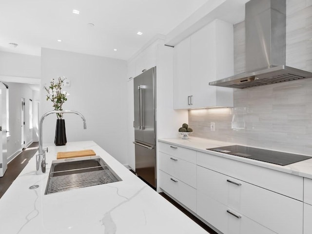 kitchen with white cabinets, extractor fan, light stone countertops, black electric cooktop, and high quality fridge