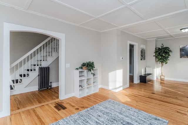 interior space with radiator heating unit, wood-type flooring, and coffered ceiling