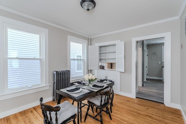 dining room with light wood-type flooring, radiator, and crown molding