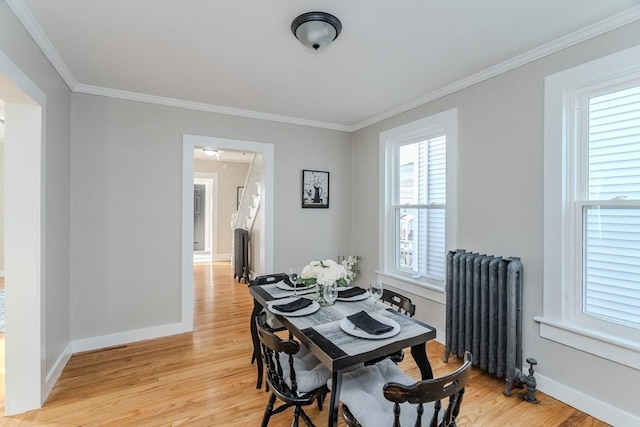 dining area featuring radiator heating unit, light hardwood / wood-style flooring, and crown molding