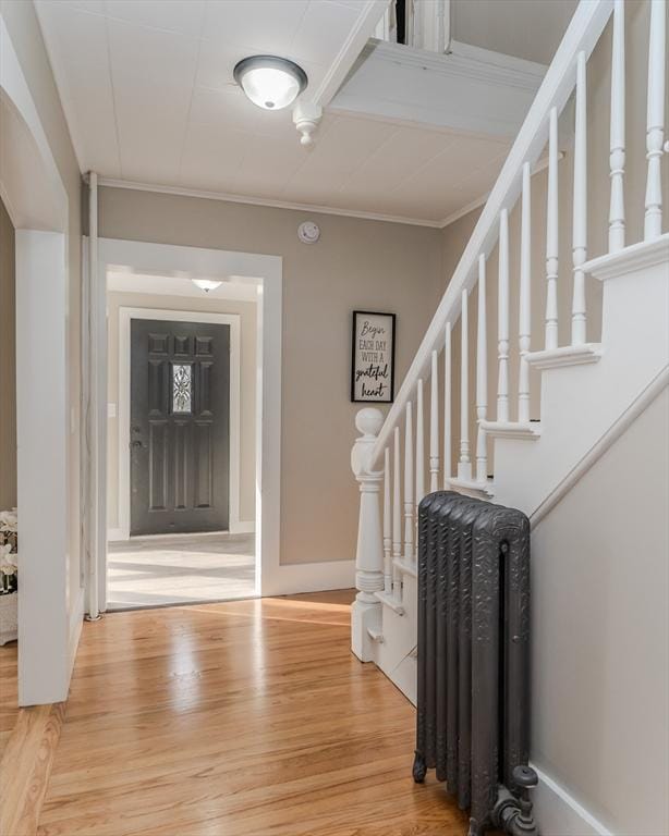 entryway with radiator, ornamental molding, and hardwood / wood-style flooring