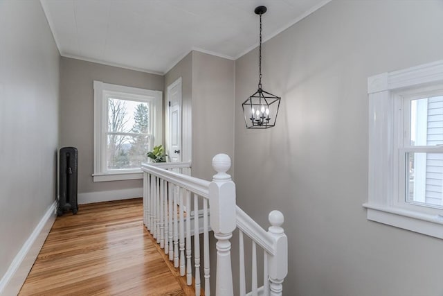 stairs featuring wood-type flooring, crown molding, and an inviting chandelier