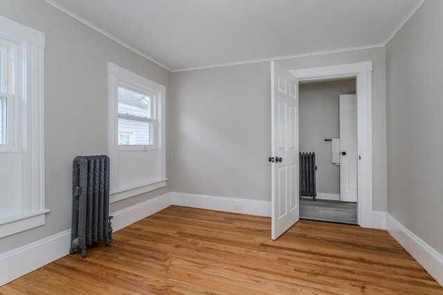 unfurnished bedroom with light hardwood / wood-style floors, crown molding, and radiator