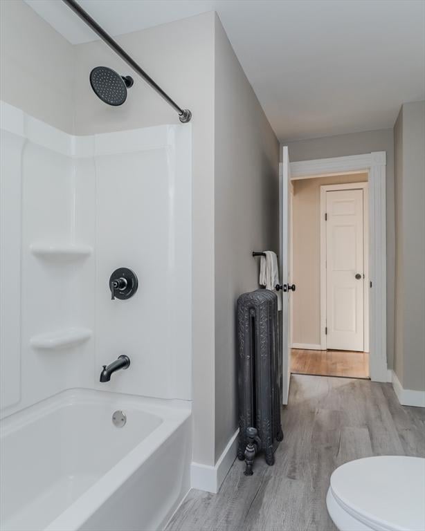 bathroom with radiator heating unit, shower / bath combination, toilet, and wood-type flooring