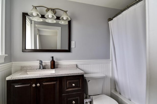 full bath with vanity, a wainscoted wall, and toilet