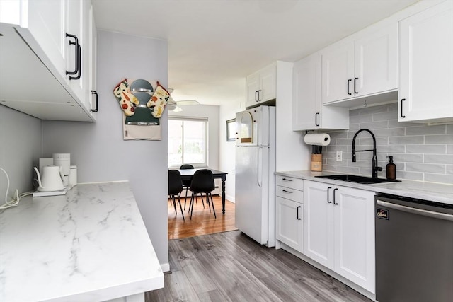 kitchen with freestanding refrigerator, decorative backsplash, wood finished floors, dishwashing machine, and a sink