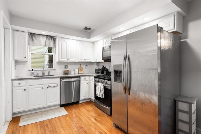 5 Hinckley St Unit 2, Somerville, MA 02145 - kitchen with stainless steel appliances, white cabinets, light stone countertops, light wood-style flooring, and recessed lighting