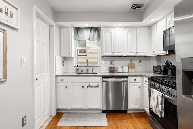 5 Hinckley St Unit 2, Somerville, MA 02145 - kitchen featuring stainless steel appliances, white cabinetry, light stone counters, tasteful backsplash, and recessed lighting
