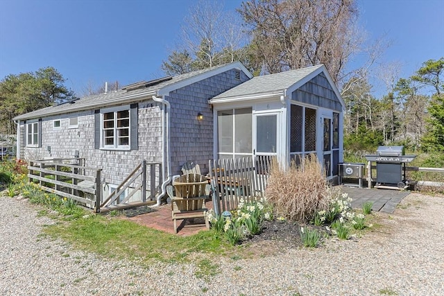 back of house with a sunroom and a shingled roof