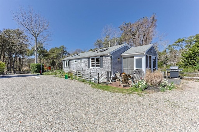 rear view of property with roof mounted solar panels and a sunroom