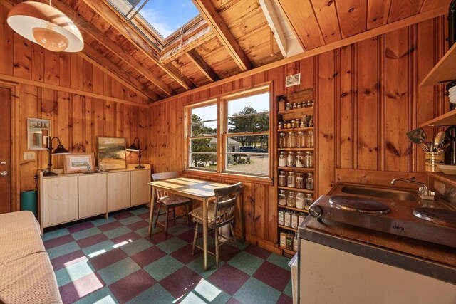 dining room with wooden walls, vaulted ceiling with skylight, dark floors, and wooden ceiling