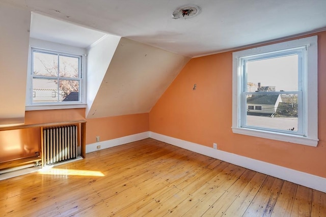 bonus room with wood-type flooring, vaulted ceiling, and radiator heating unit