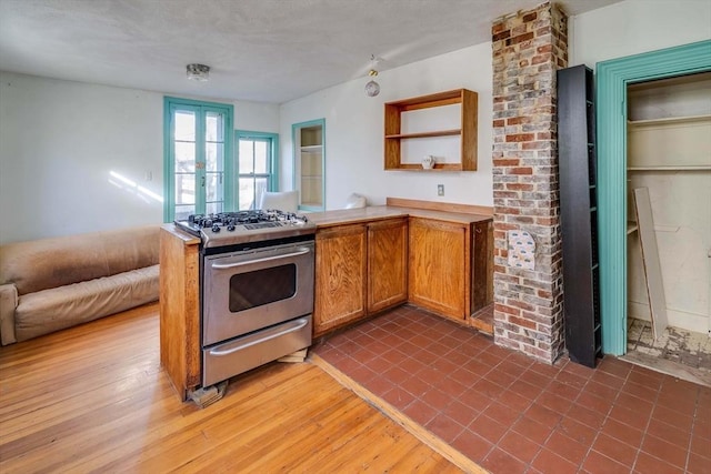 kitchen with french doors, wood-type flooring, stainless steel gas range, and kitchen peninsula