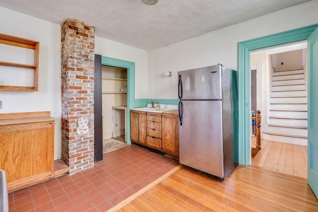 kitchen featuring sink, light hardwood / wood-style floors, and stainless steel refrigerator