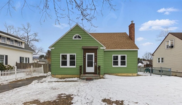 view of front of property featuring a shingled roof, a chimney, and fence