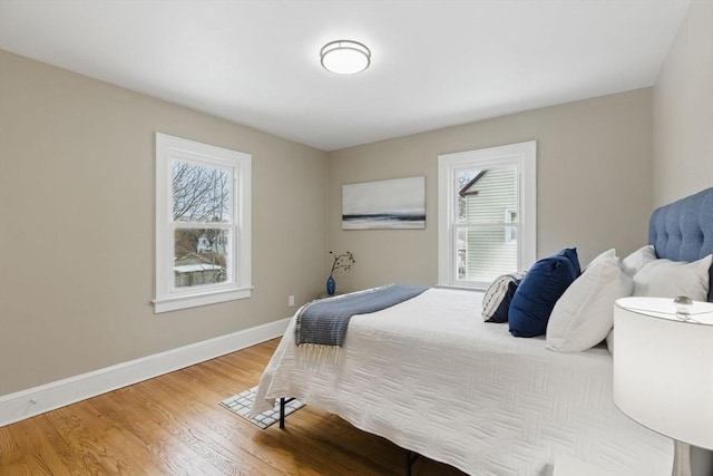 bedroom featuring multiple windows, wood finished floors, and baseboards