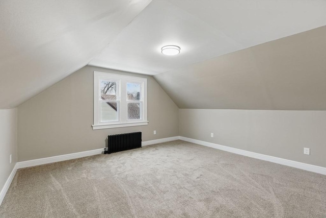 additional living space featuring lofted ceiling, radiator, carpet flooring, and baseboards