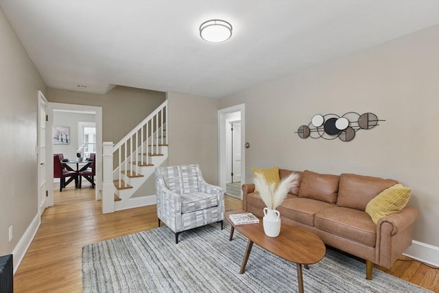 living room with light wood-style floors, baseboards, and stairway