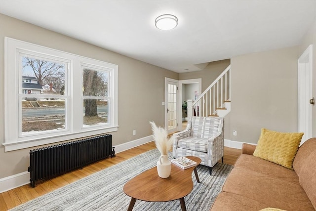 interior space with stairs, light wood finished floors, baseboards, and radiator