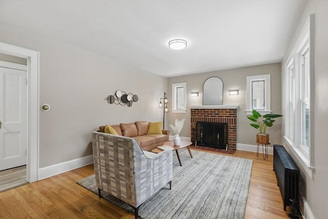 living room with radiator, light wood-style floors, and baseboards