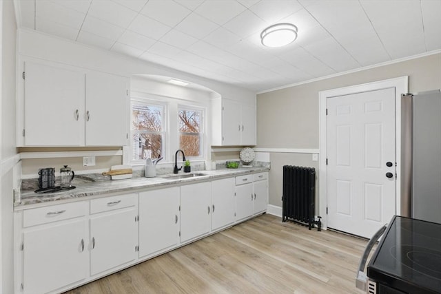 kitchen featuring black electric range, radiator, white cabinets, a sink, and stainless steel refrigerator