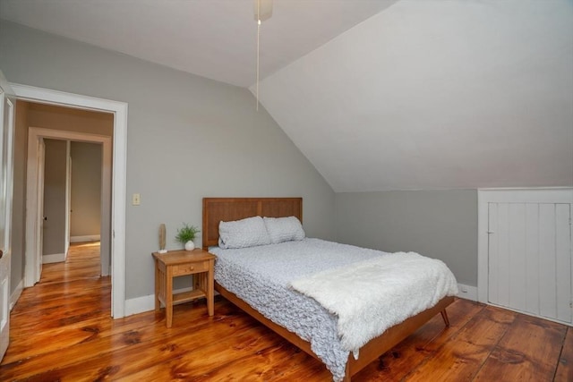 bedroom featuring lofted ceiling, wood finished floors, and baseboards