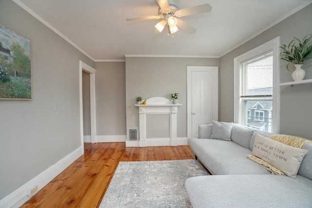 living area featuring visible vents, hardwood / wood-style floors, baseboards, ornamental molding, and a ceiling fan