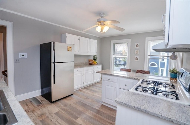kitchen with white cabinets, range with gas cooktop, light wood finished floors, and freestanding refrigerator