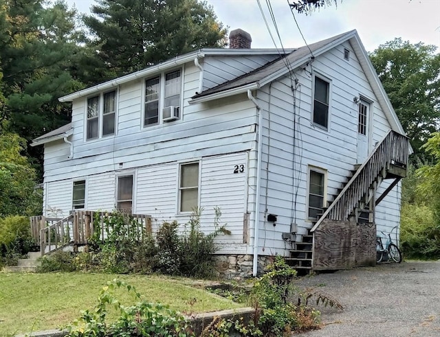 rear view of property with a lawn and cooling unit