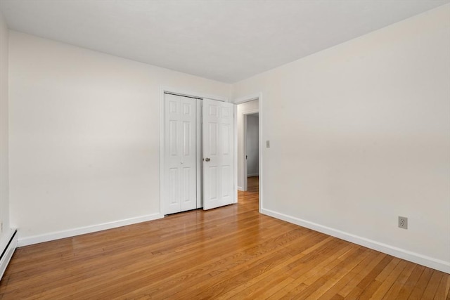 unfurnished room featuring light wood finished floors, baseboard heating, and baseboards