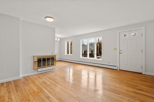 unfurnished living room featuring baseboards, a fireplace, an inviting chandelier, hardwood / wood-style flooring, and a baseboard radiator