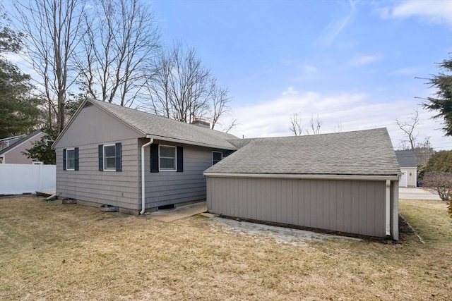 view of side of home with a lawn, a chimney, fence, and a shingled roof