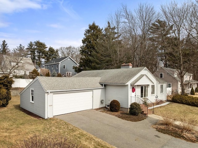 view of front of house with an attached garage, a front yard, roof with shingles, a chimney, and driveway