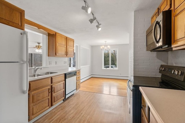 kitchen featuring white appliances, light wood-style flooring, a sink, light countertops, and baseboard heating