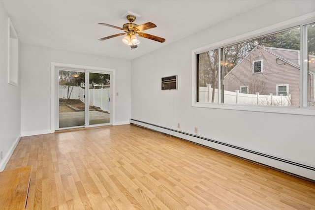 empty room with baseboards, baseboard heating, wood finished floors, a wall mounted AC, and a ceiling fan