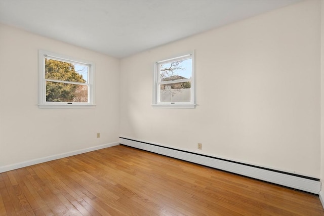 empty room with light wood-style flooring, plenty of natural light, baseboards, and a baseboard radiator