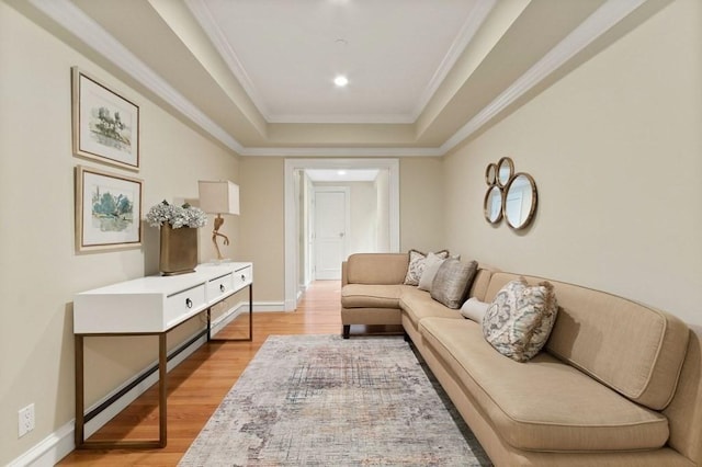 living room featuring light wood-type flooring, a tray ceiling, and ornamental molding