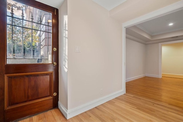 entrance foyer featuring light wood-type flooring, crown molding, and a tray ceiling