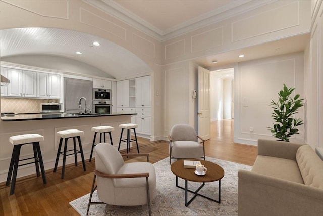 living room featuring crown molding, sink, and hardwood / wood-style flooring