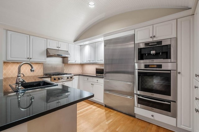 kitchen featuring white cabinetry, sink, vaulted ceiling, and appliances with stainless steel finishes