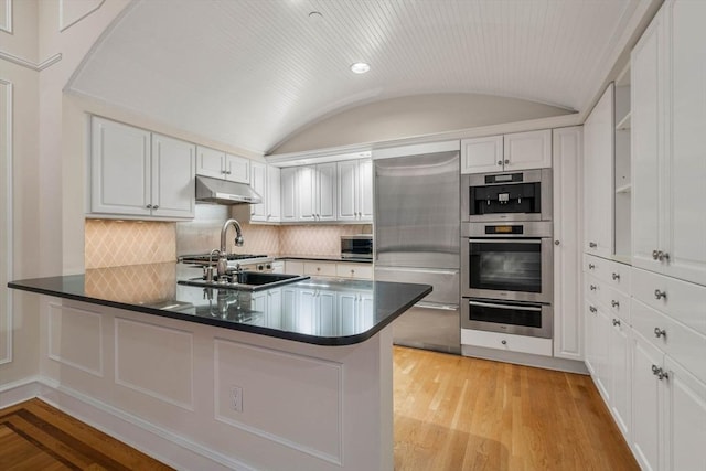 kitchen featuring white cabinets, stainless steel appliances, lofted ceiling, and brick ceiling