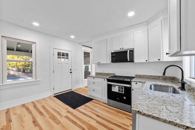 kitchen featuring light stone counters, a wealth of natural light, sink, white cabinetry, and appliances with stainless steel finishes