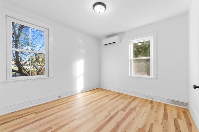 empty room featuring light hardwood / wood-style floors, a wealth of natural light, and a wall mounted AC