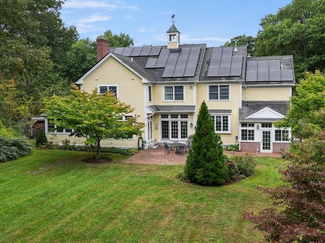 back of property featuring a patio, solar panels, and a yard